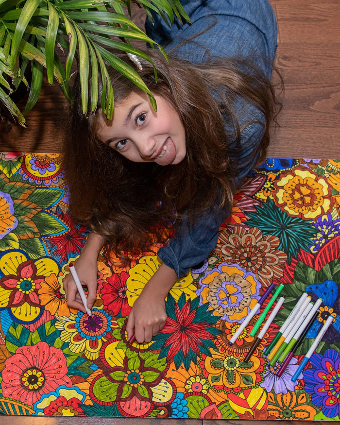 Girl lying on a giant colored Flowers coloring poster
